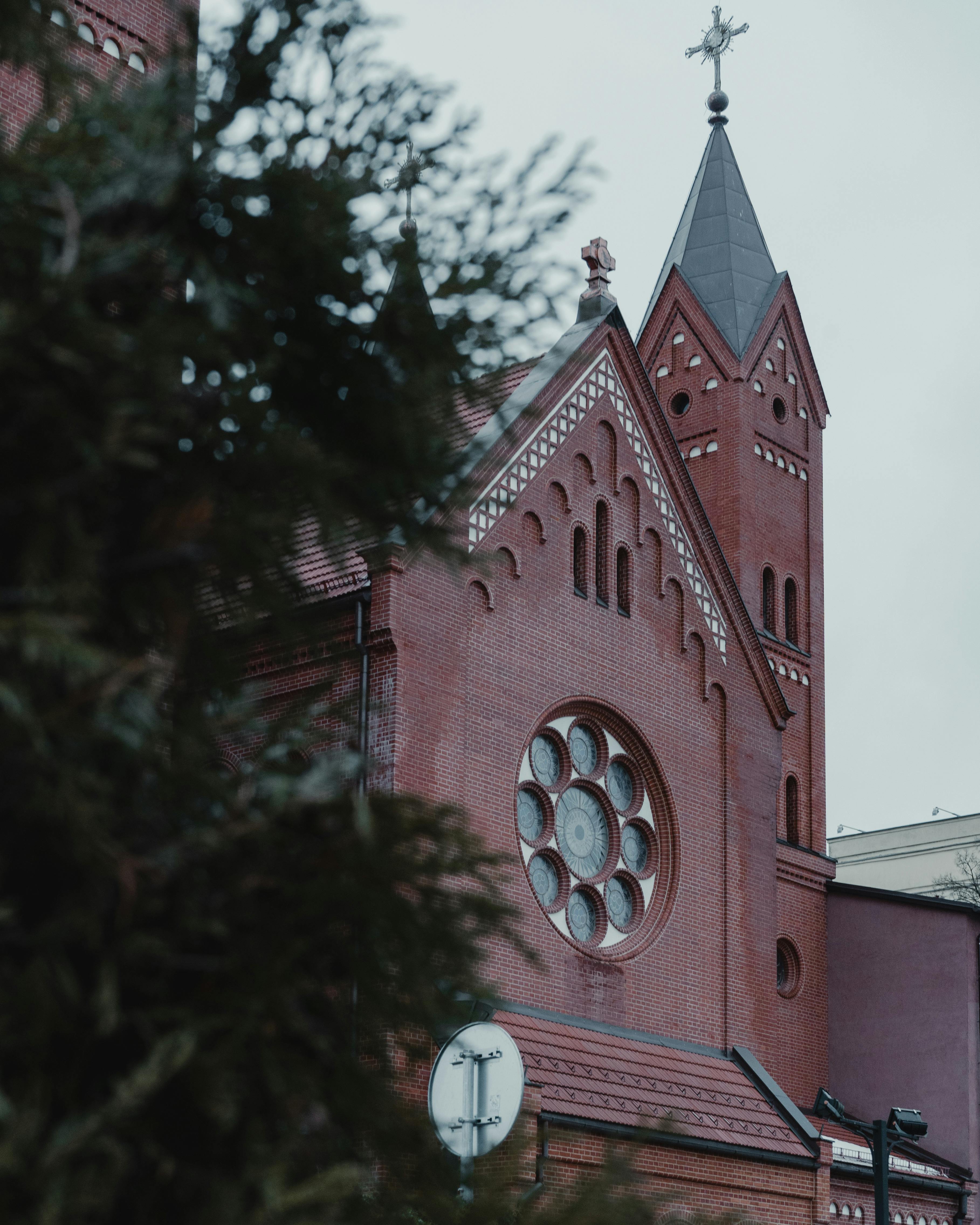 a church with a steeple and a tree in the background