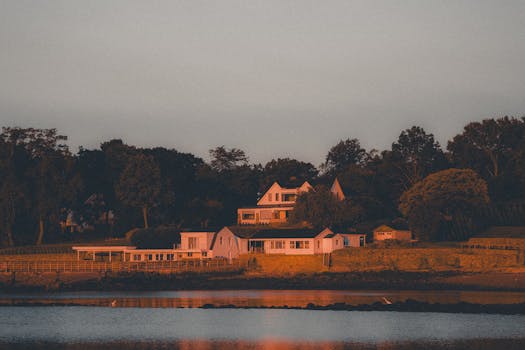 A picturesque waterfront house in Stamford, CT, bathed in warm sunset light, reflecting tranquility.
