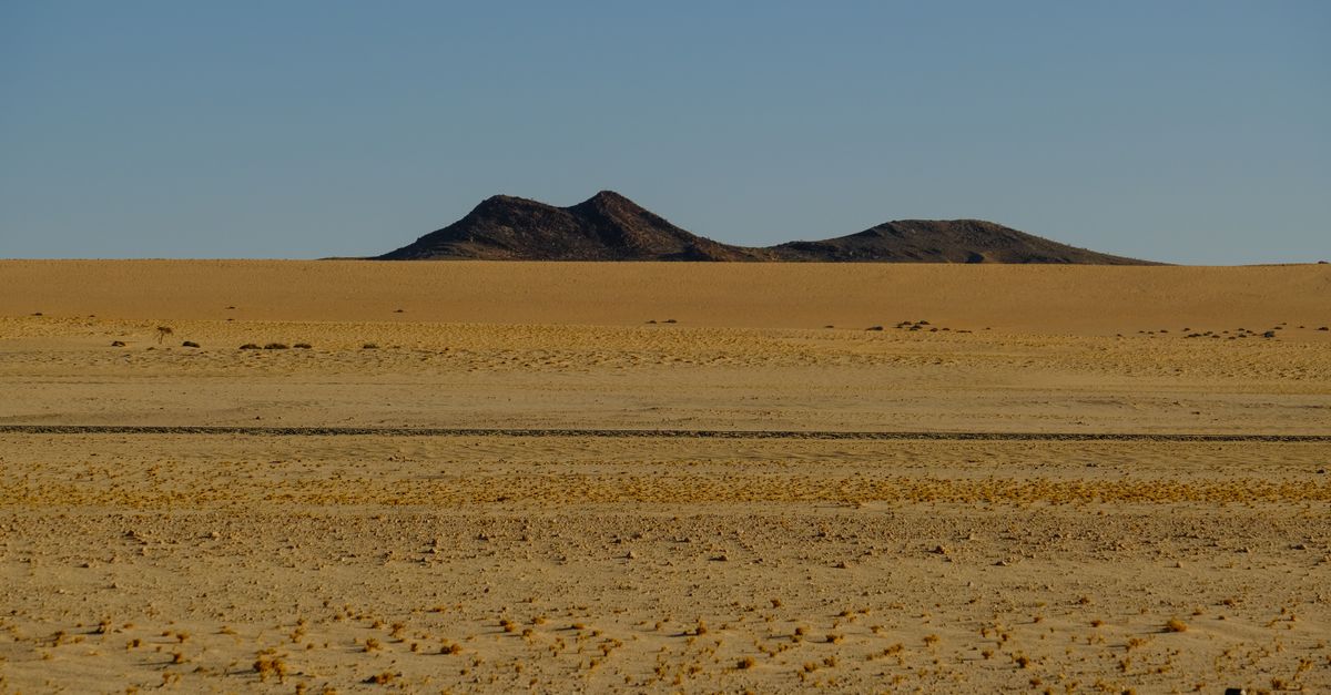 Nolan's 'The Odyssey' Filming in Western Sahara Reignites Territorial Dispute A remote desert landscape with distant hills under a clear blue sky.