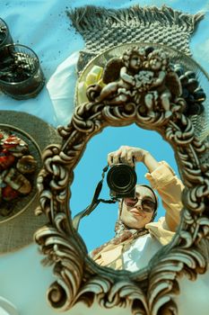 Vintage mirror reflection of a photographer capturing a unique artistic shot.