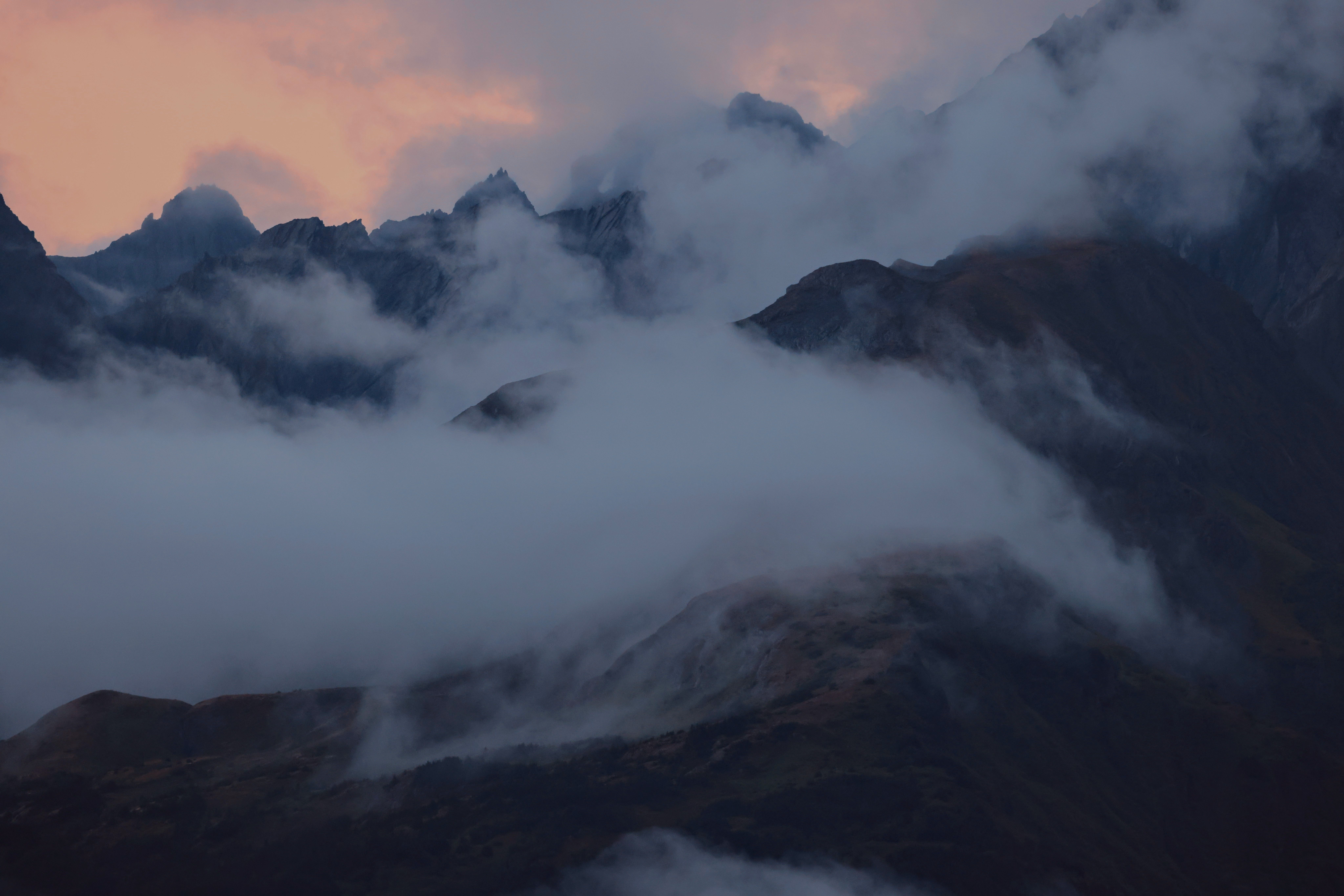 A mountain range with clouds and fog at sunset · Free Stock Photo