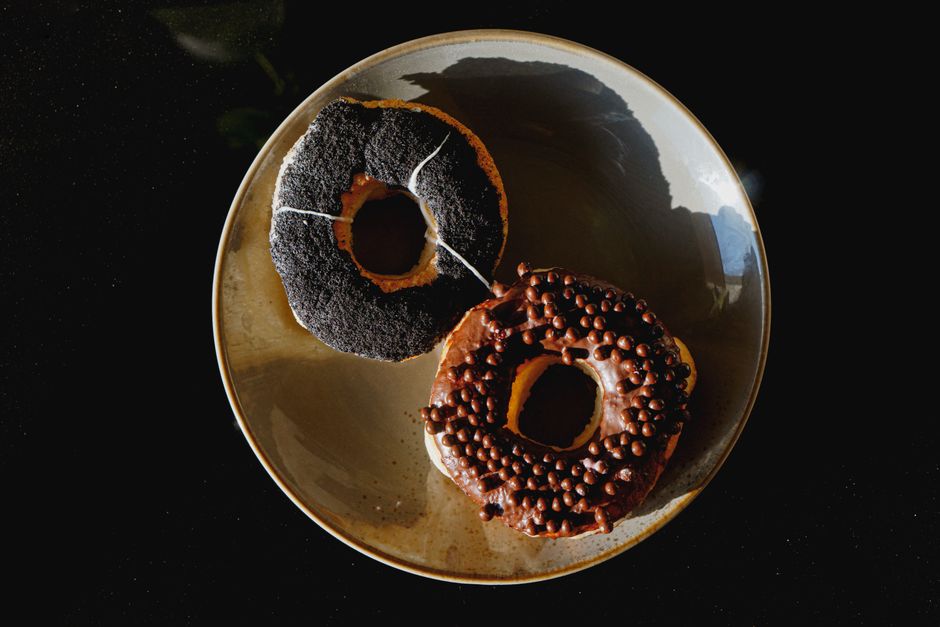 Two scrumptious donuts, one chocolate glazed with sprinkles, captured on a plate.