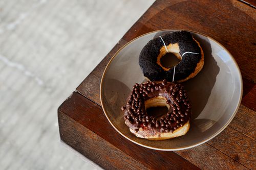 Free Close-up of chocolate and black-topped donuts on a wooden table, perfect for breakfast or dessert. Stock Photo