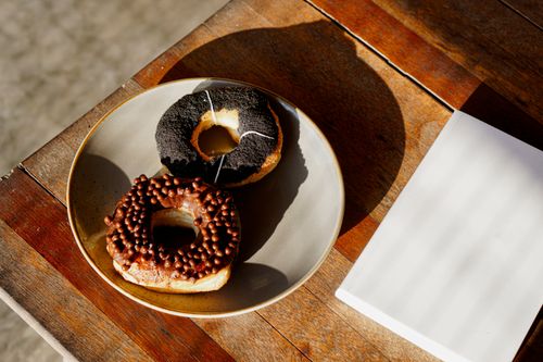 Free Two donuts with chocolate and glaze toppings served on a plate, ideal for breakfast. Stock Photo