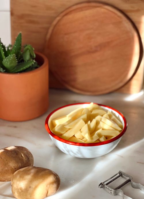 Free Sliced potatoes ready for cooking in a rustic kitchen setting with natural light. Stock Photo