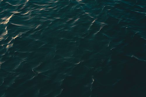 Free A close-up view of a dark ocean surface with gentle ripples under soft lighting. Stock Photo