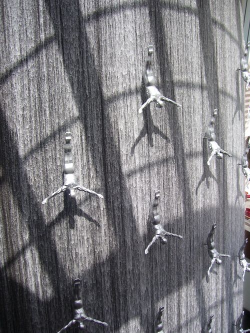 Free Silver diver sculptures adorn a waterfall wall, creating dynamic artistic impact. Stock Photo