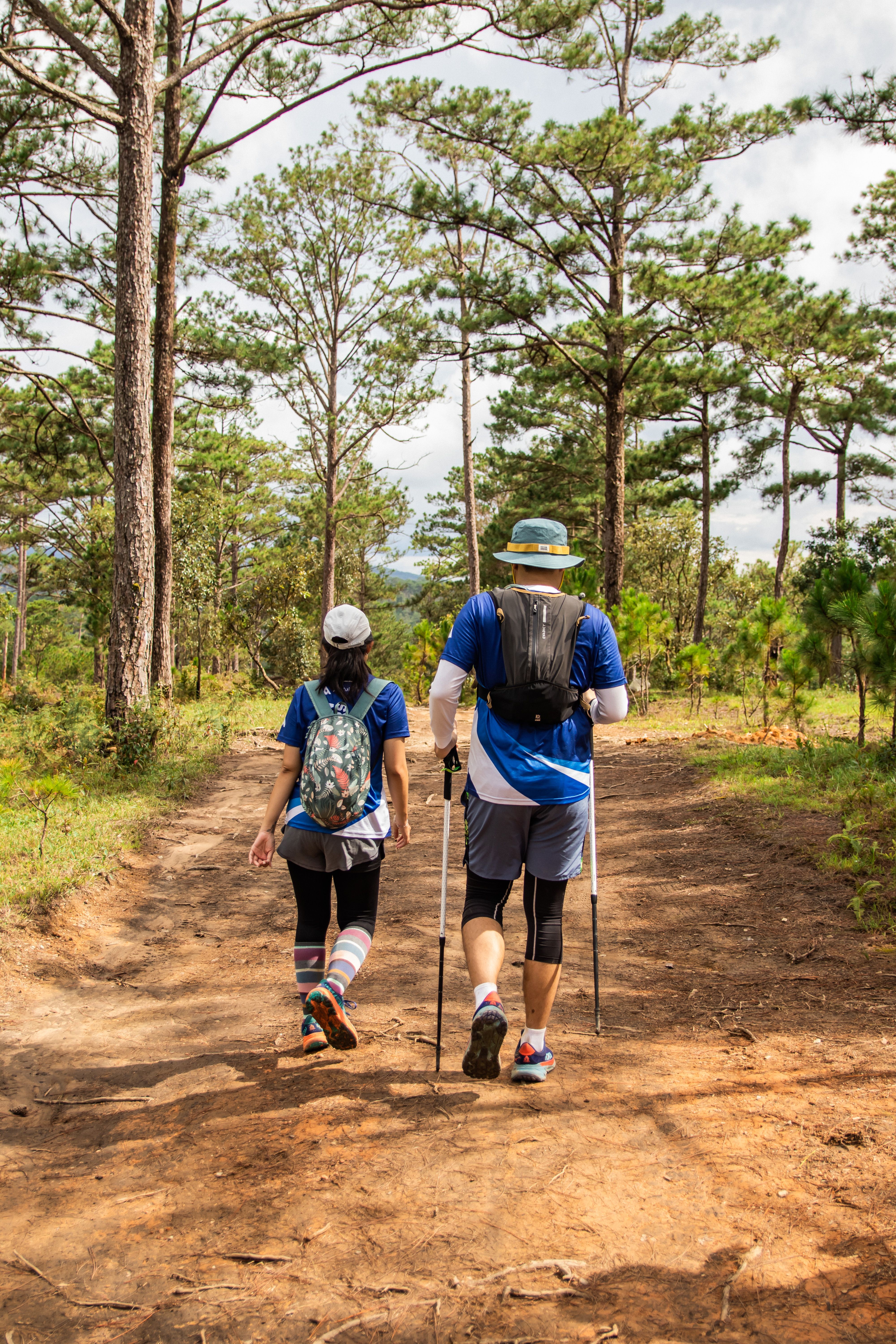 Two people walking down a dirt path in the woods · Free Stock Photo