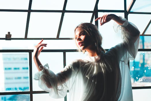 Graceful young woman posing indoors by a window with soft sunlight.