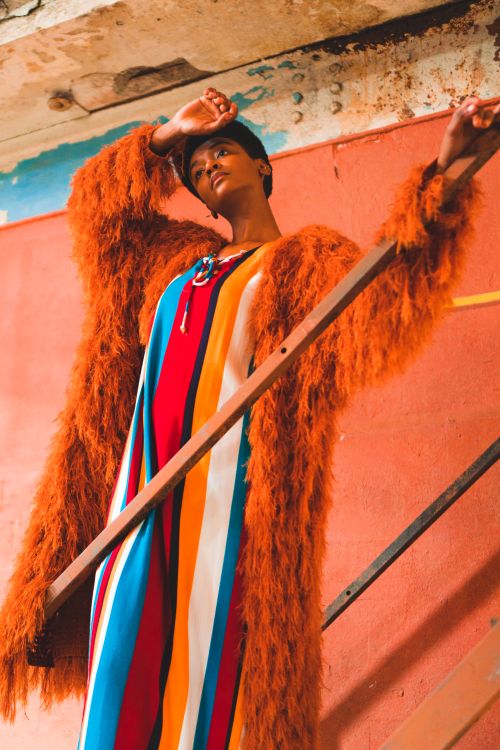 Free Vibrant editorial fashion portrait of a model in a colorful fur coat, striking a pose outdoors. Stock Photo