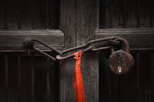 A rusty padlock and chain securing an old wooden door, symbolizing security and secrecy.