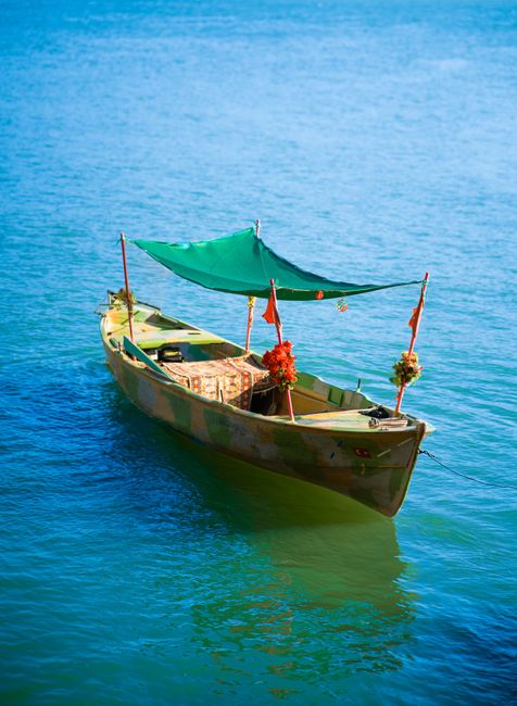 A colorful wooden boat with decorations gently floats on clear blue waters in Bursa, Türkiye.