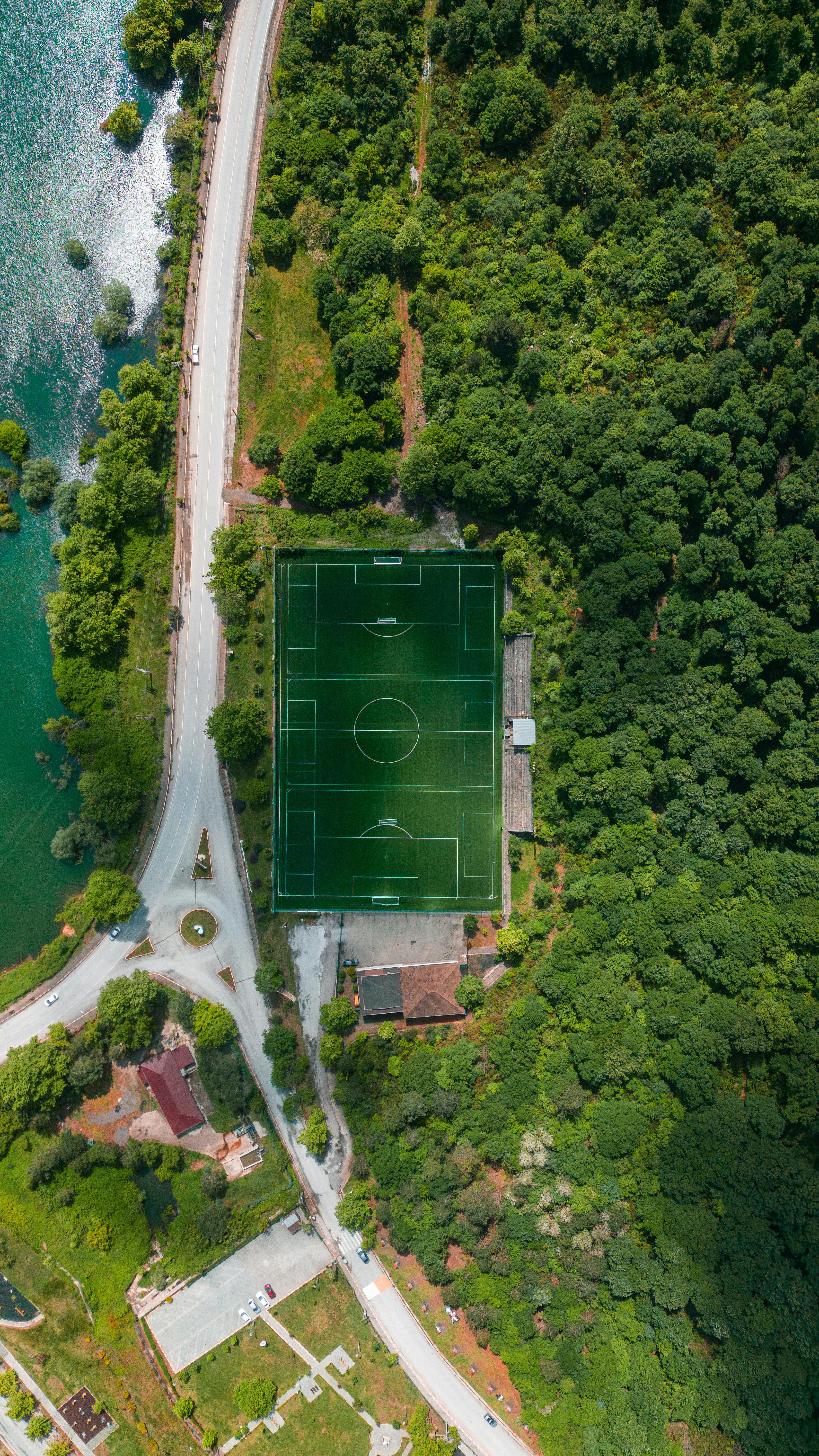 Discover an aerial view of a lush forest surrounding a sports field and a nearby lake in Bursa, Türkiye.
