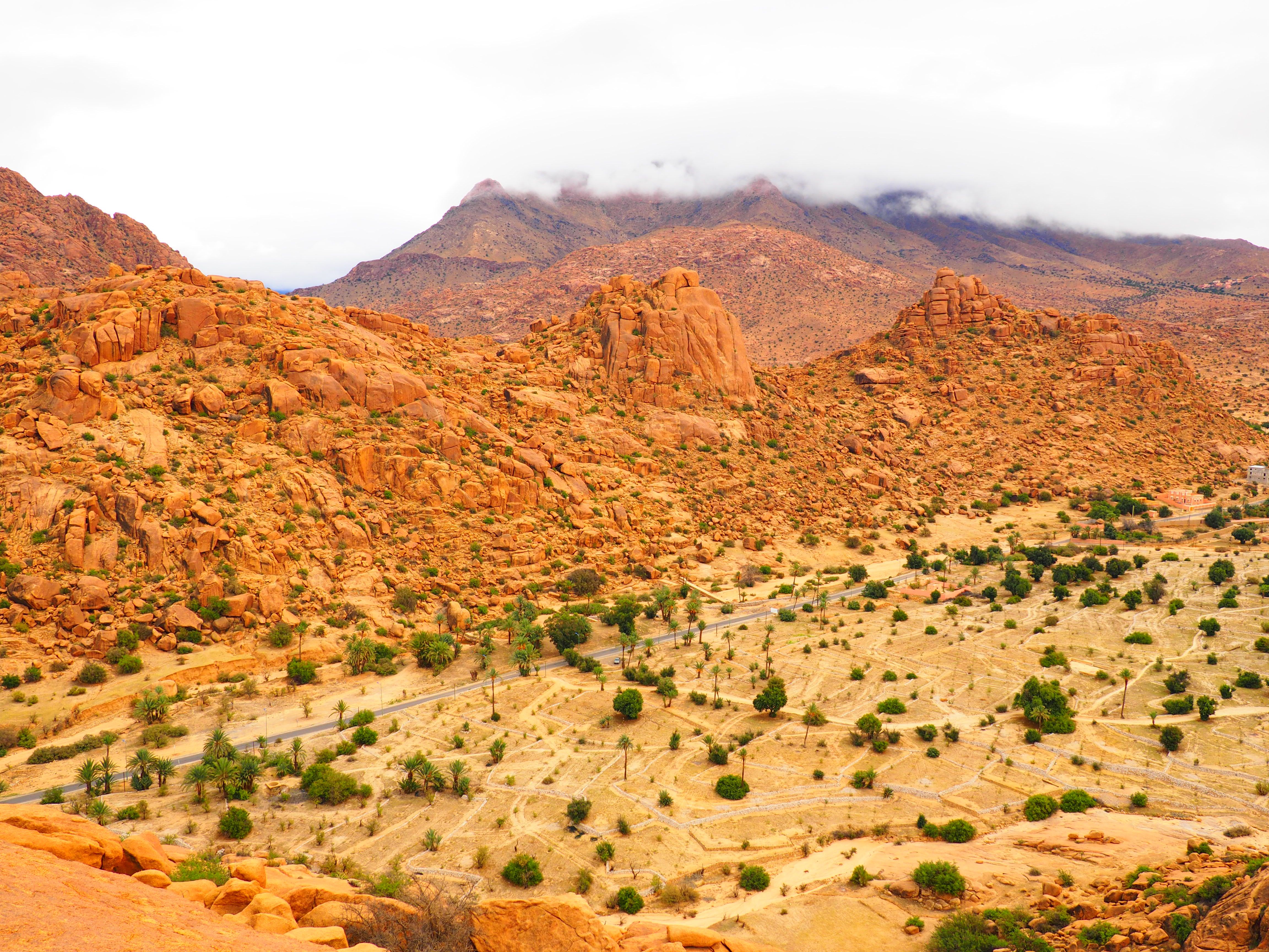 Aerial view of the vibrant red sandstone hills in Tafraout, Morocco, showcasing a dramatic desert landscape.