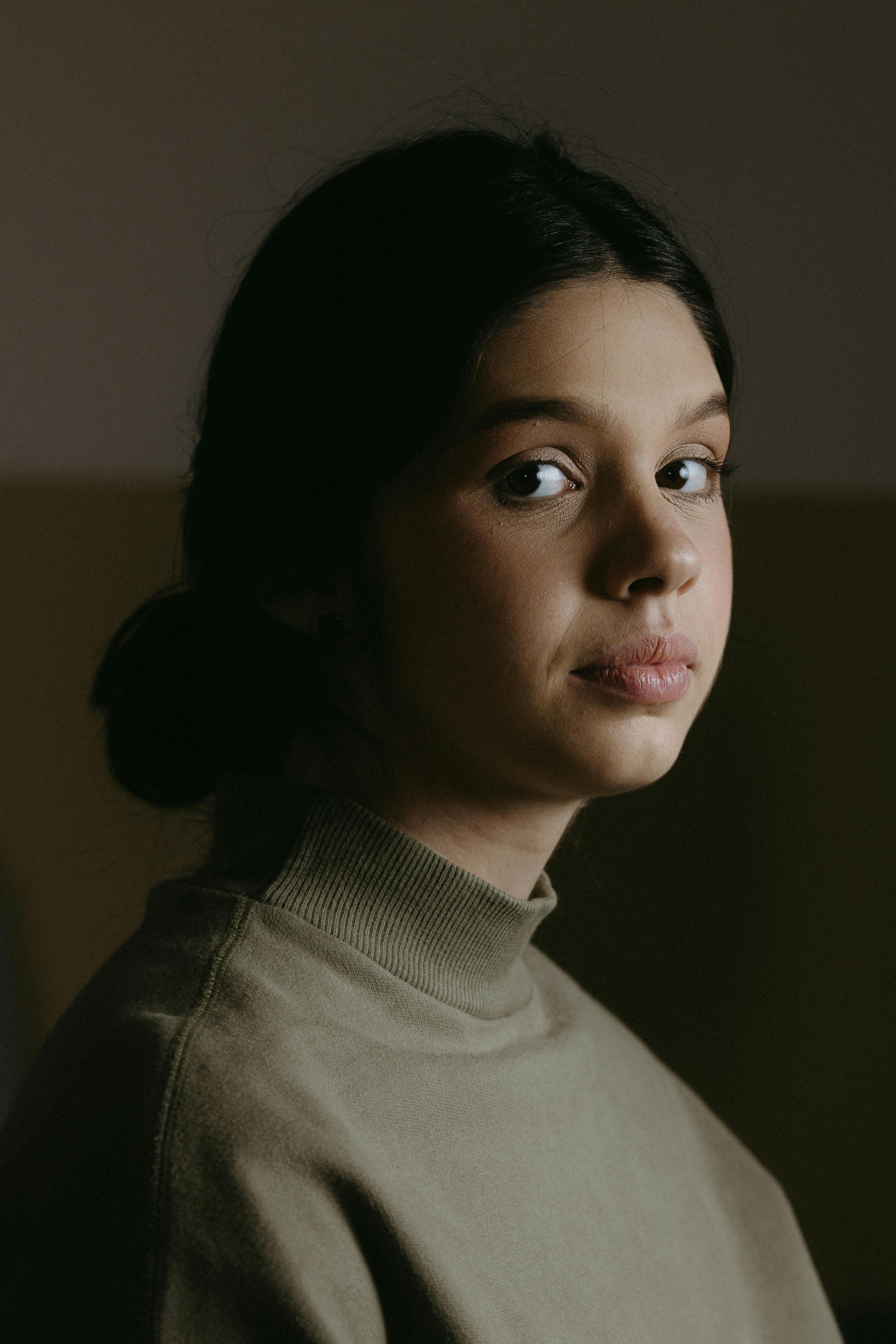 Portrait of a young woman in knitwear with a pensive expression, indoors.
