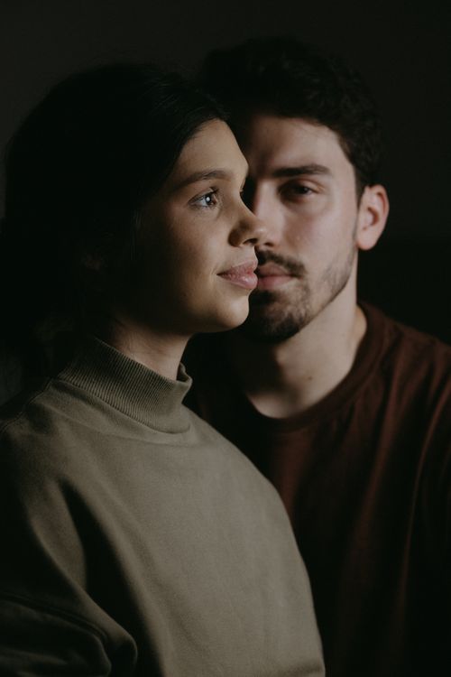 Free A serene and intimate portrait of a young couple embracing in low light, capturing affection and connection. Stock Photo