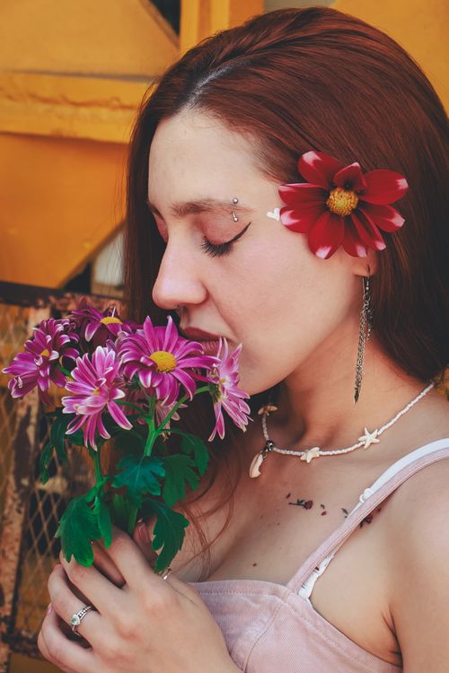 Free A woman in São Paulo holding flowers, eyes closed, with floral accessories. Stock Photo