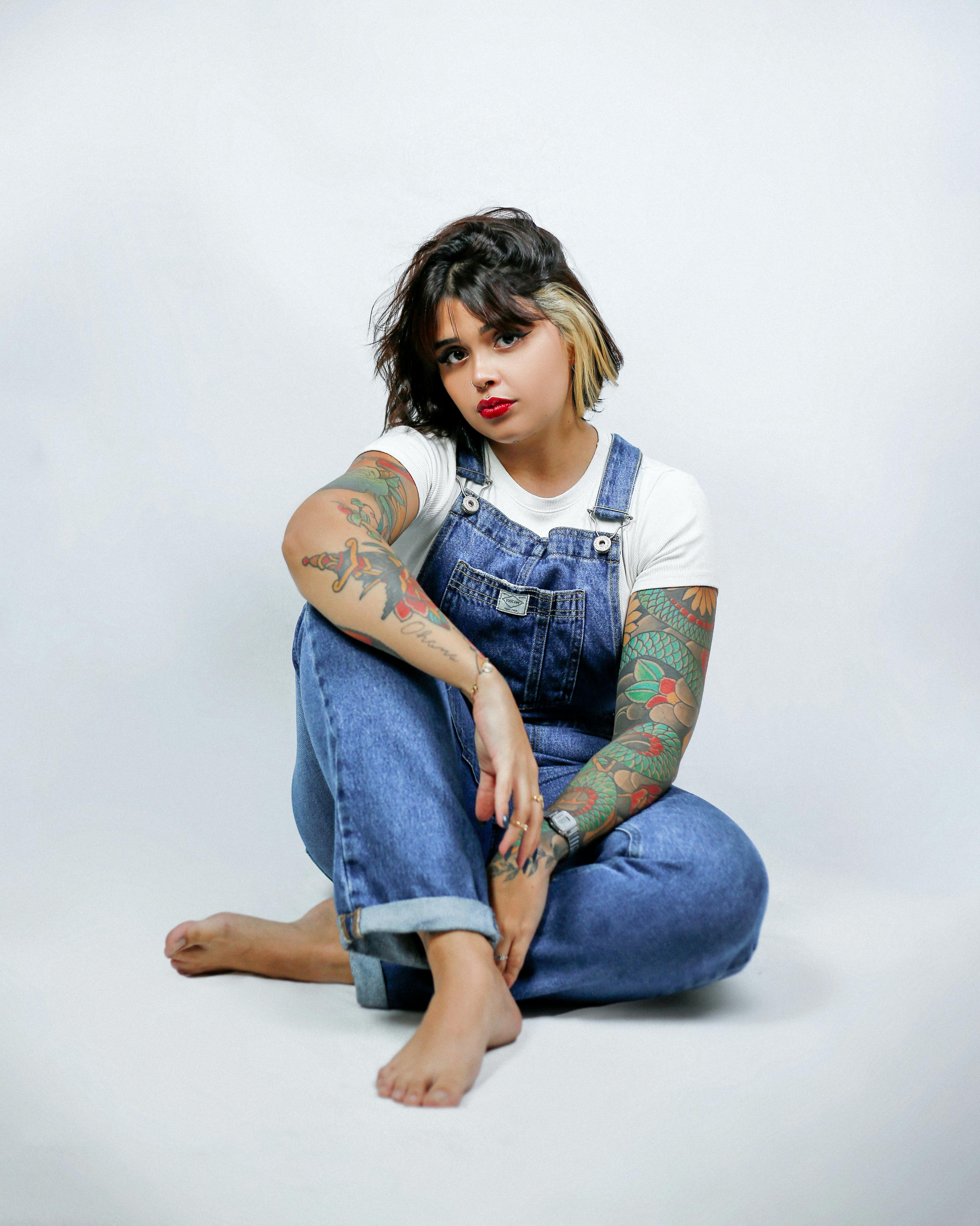 a woman with tattoos sitting on the ground