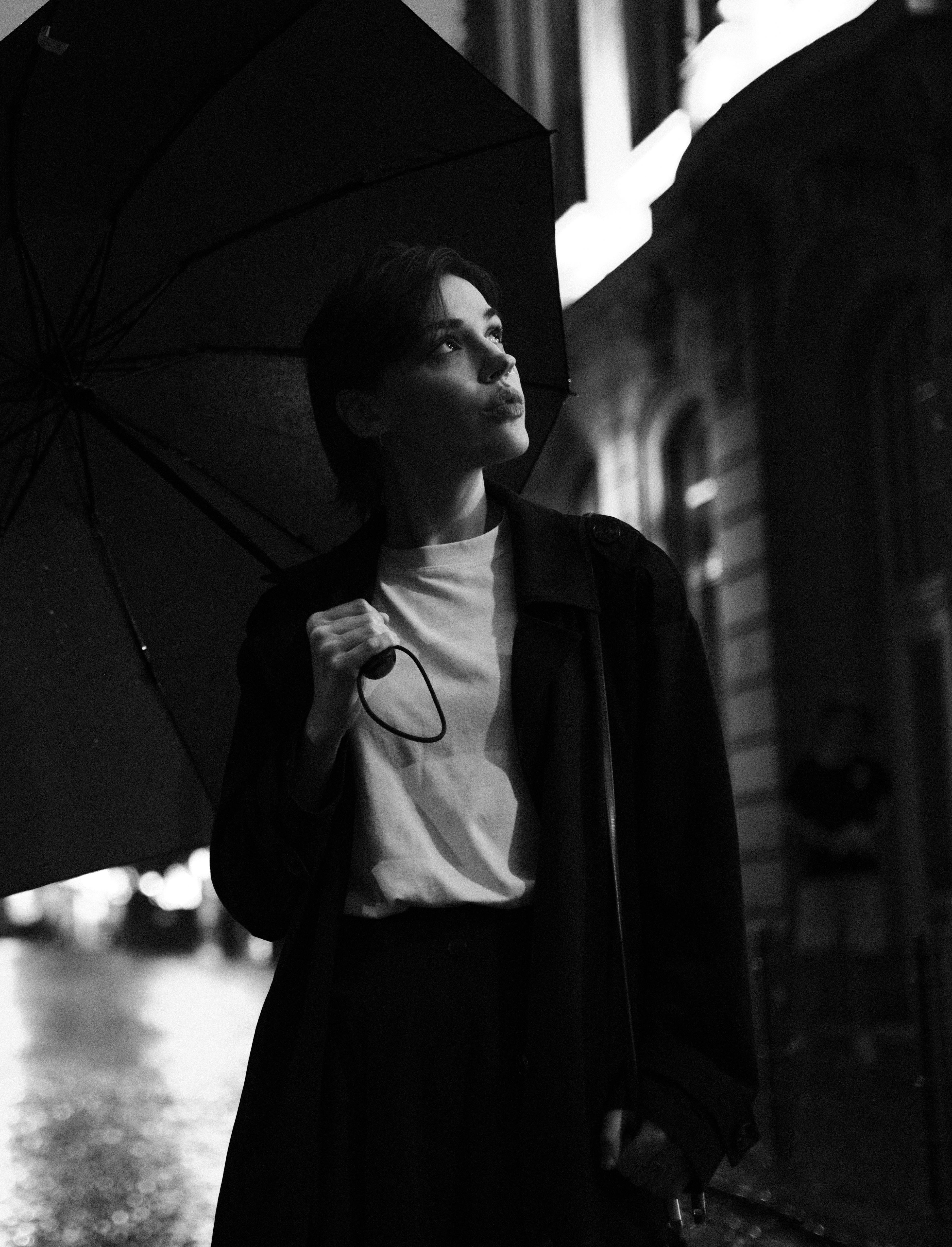 Fashionable woman with umbrella in black and white on a rainy night in Cologne.