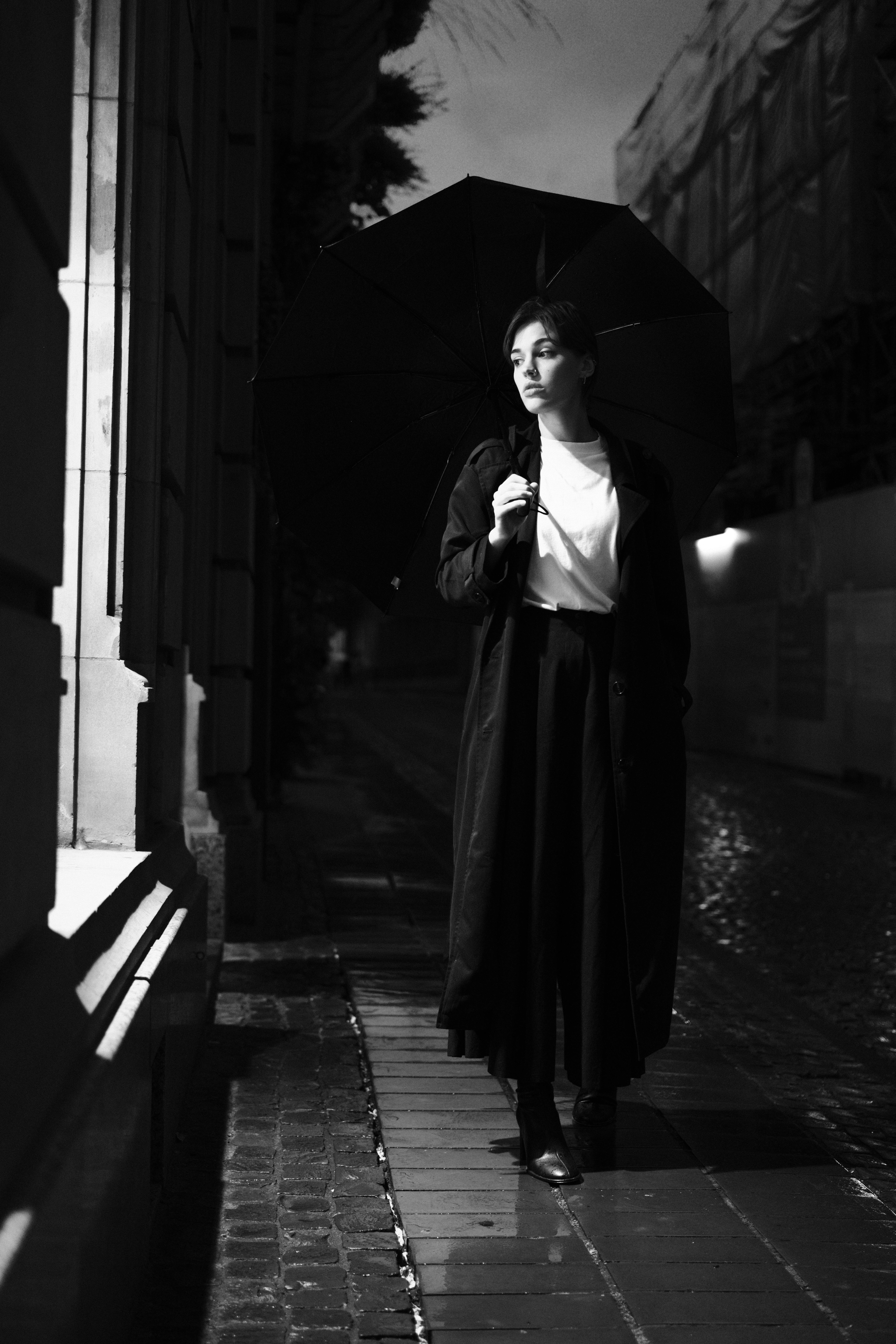 a woman in a long coat and hat is walking down the street