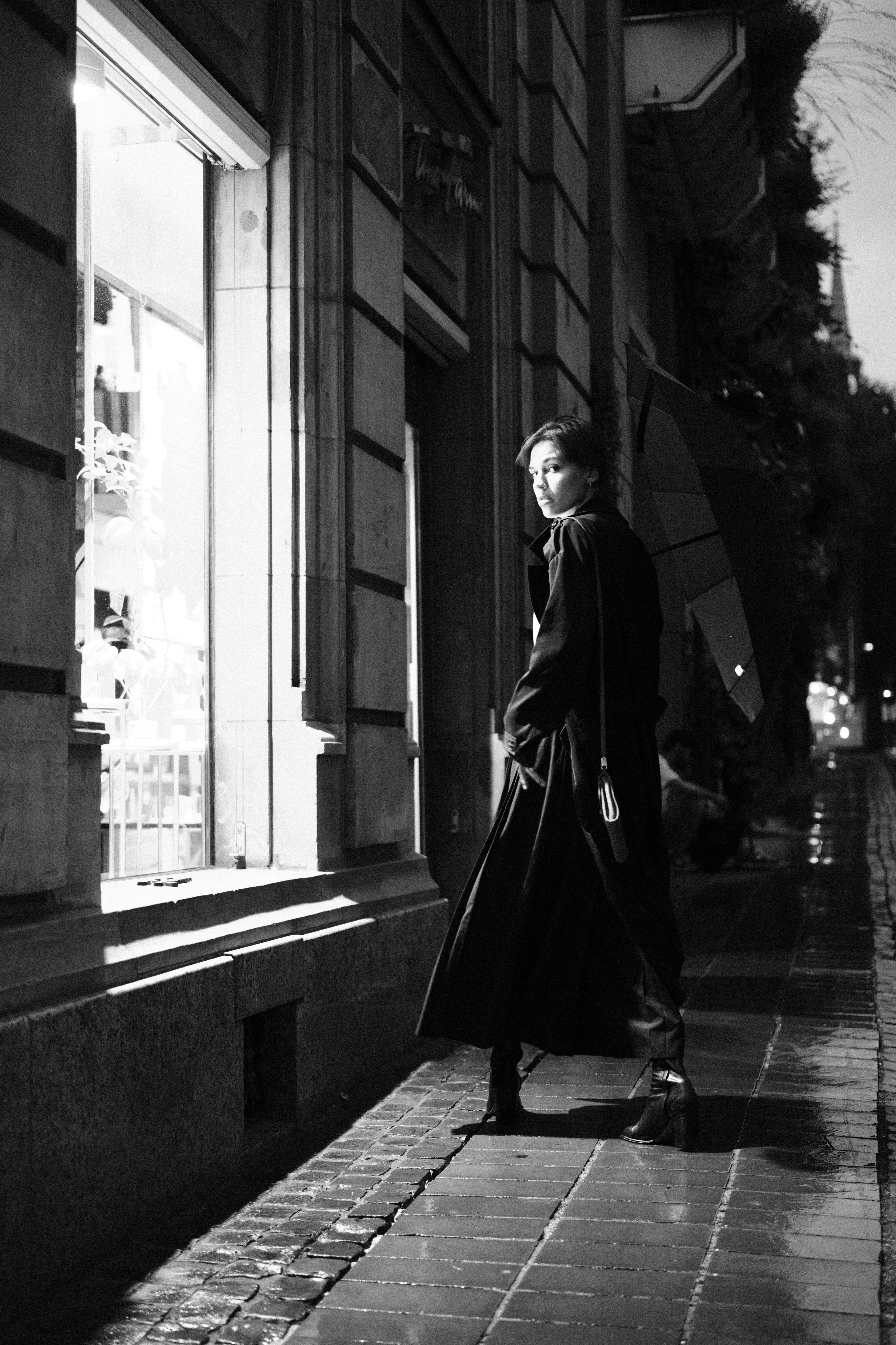 A woman in a trench coat is walking down a sidewalk · Free Stock Photo