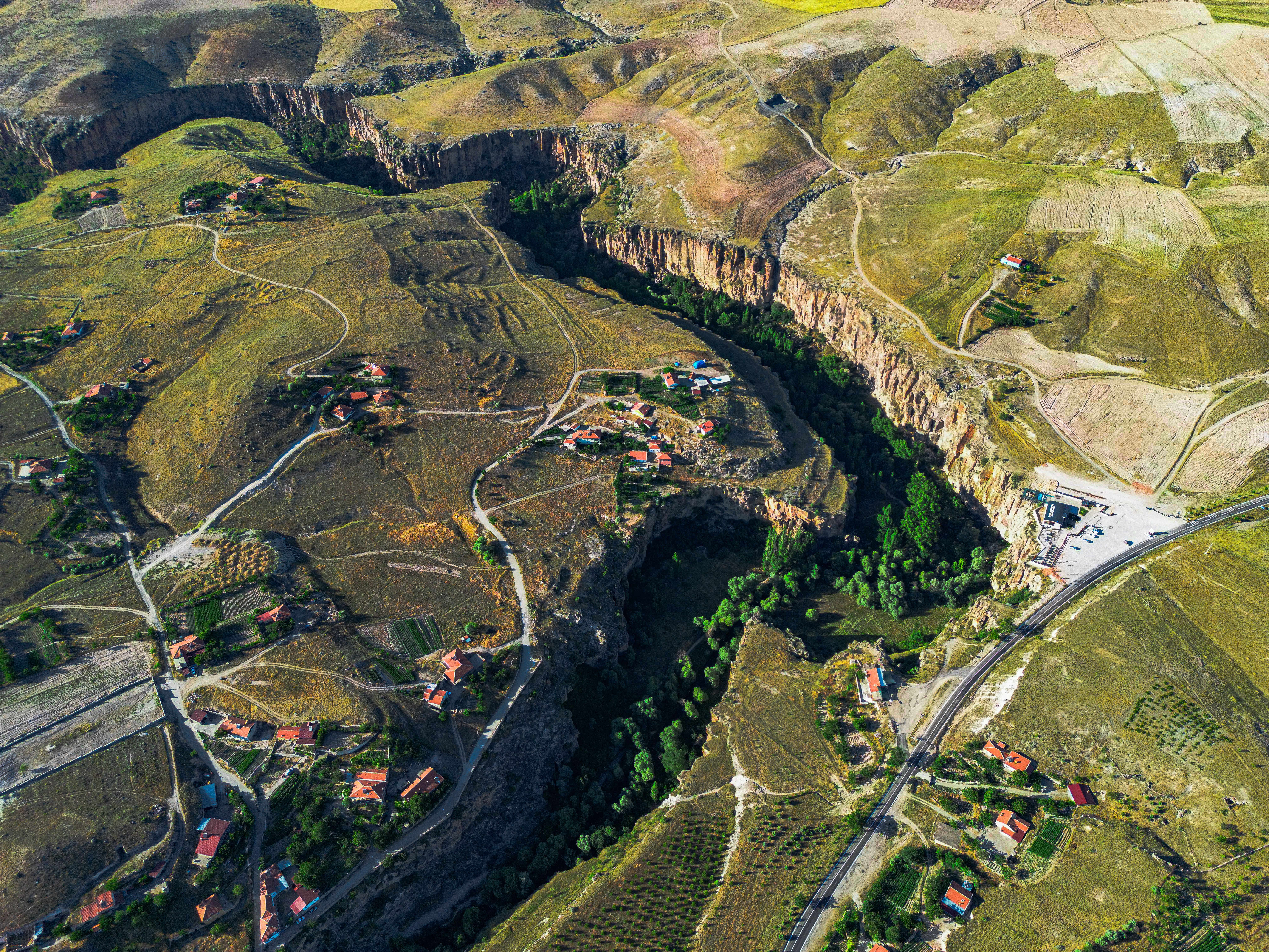 A breathtaking aerial view of a rural landscape featuring canyons, fields, and scattered houses.