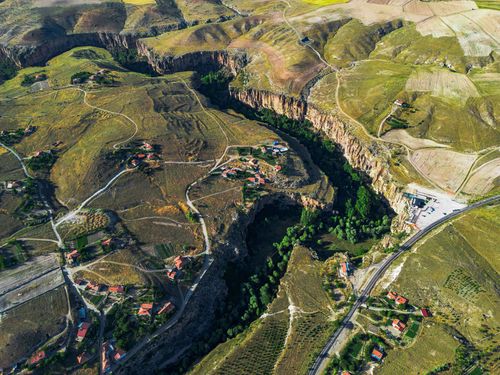 Free A breathtaking aerial view of a rural landscape featuring canyons, fields, and scattered houses. Stock Photo