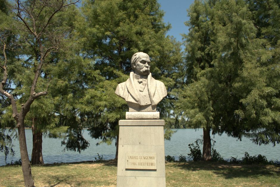 Stone bust of Taras Shevchenko in a lush park in Bucharest, Romania.