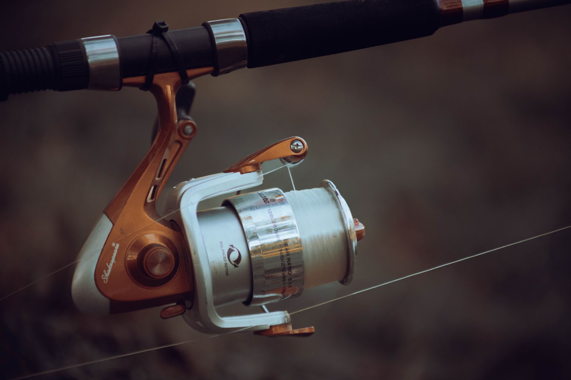 Detailed view of a fishing reel with line tension, showcasing precise fishing equipment mechanics.