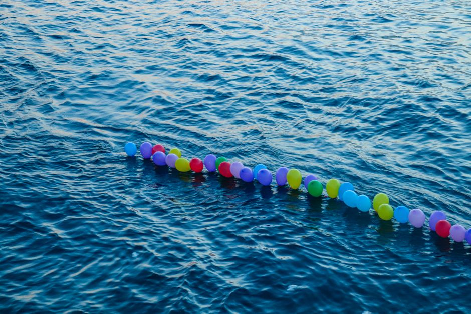 A vibrant display of balloons floating peacefully on the ocean waves.