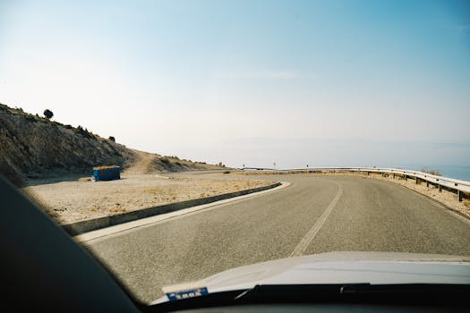Experience the serene drive on a coastal road in Vlora, Albania, under the sunny skies.