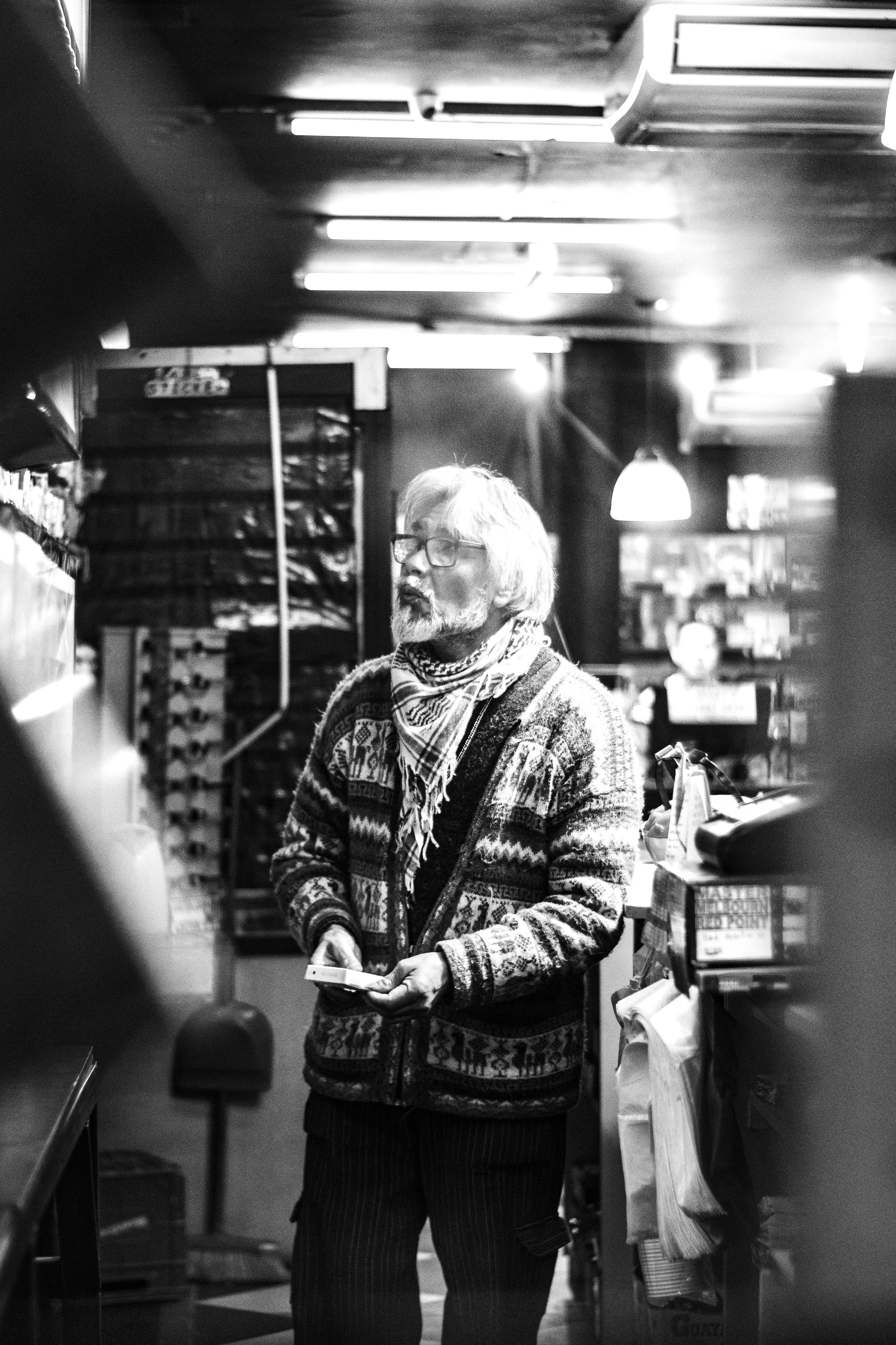 Black and white image of a man in a Buenos Aires shop, capturing street photography essence.