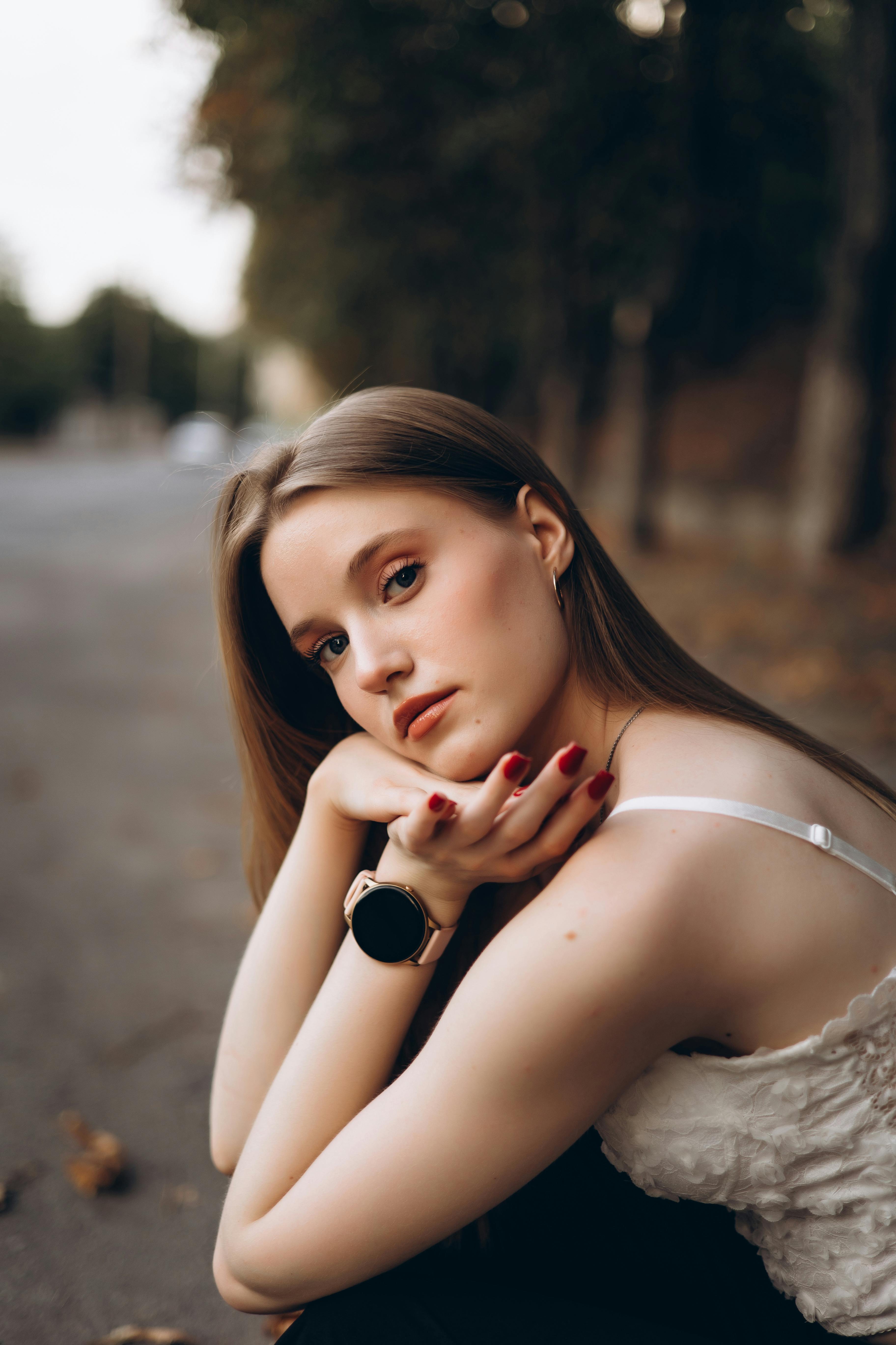 a beautiful woman sitting on the ground with her hand on her wrist