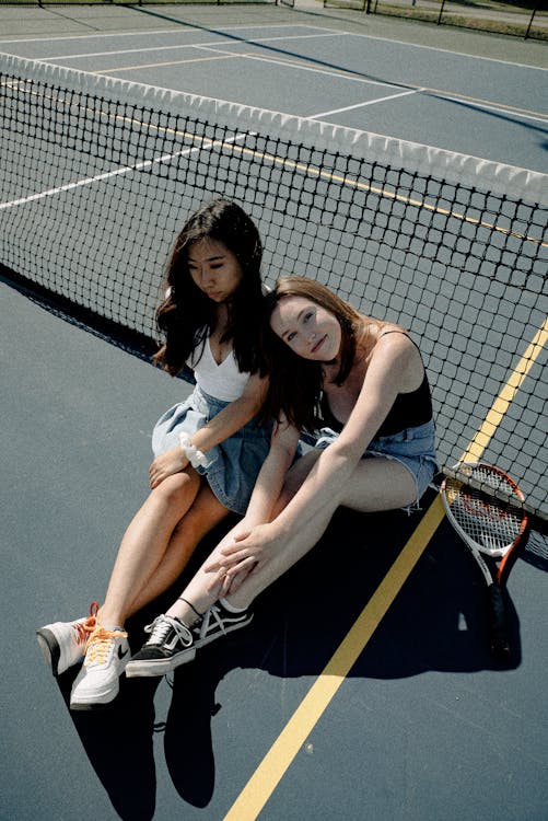 Photo Of Two Women Sitting on Tennis Court