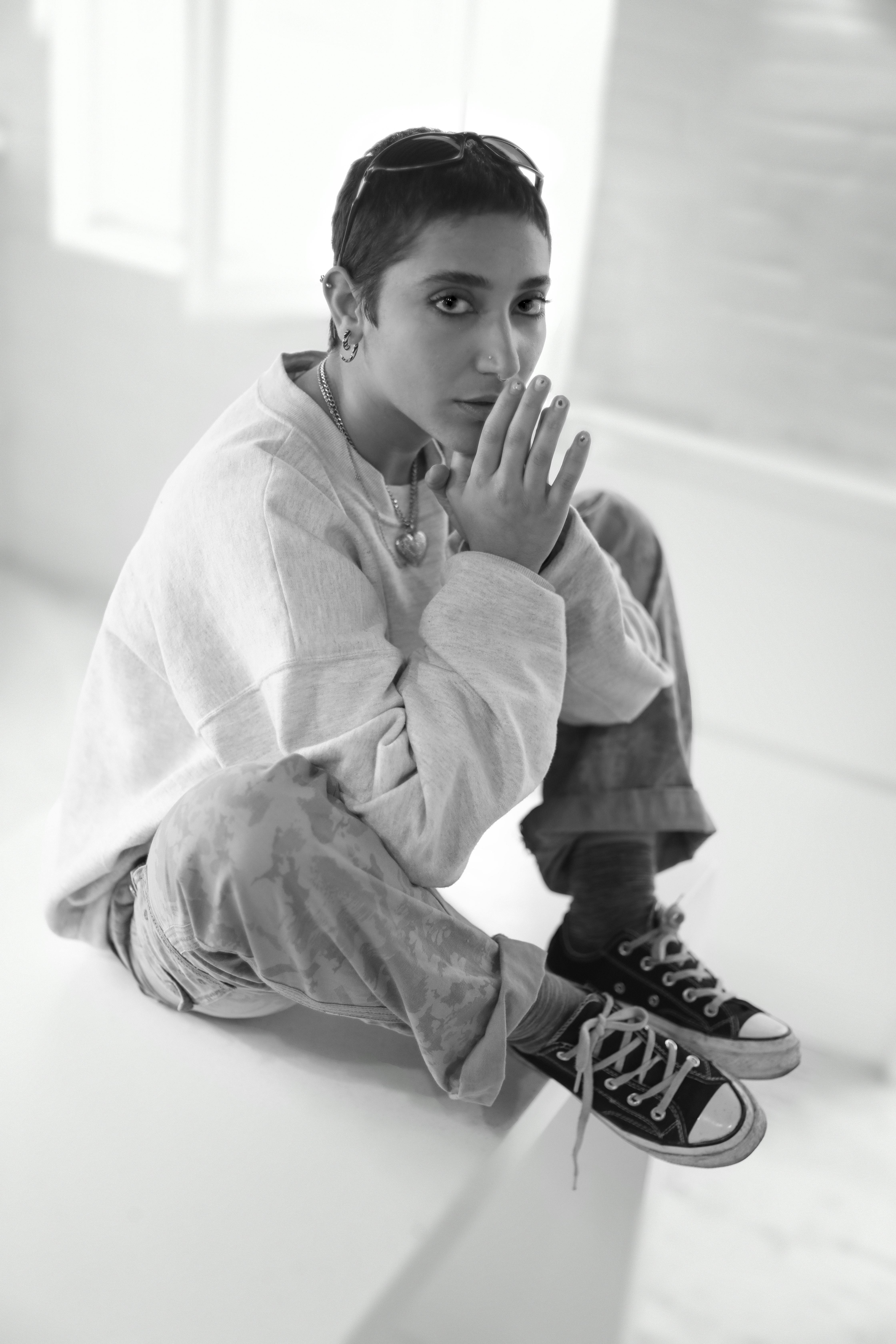 a young man sitting on a bench with his hands on his chin