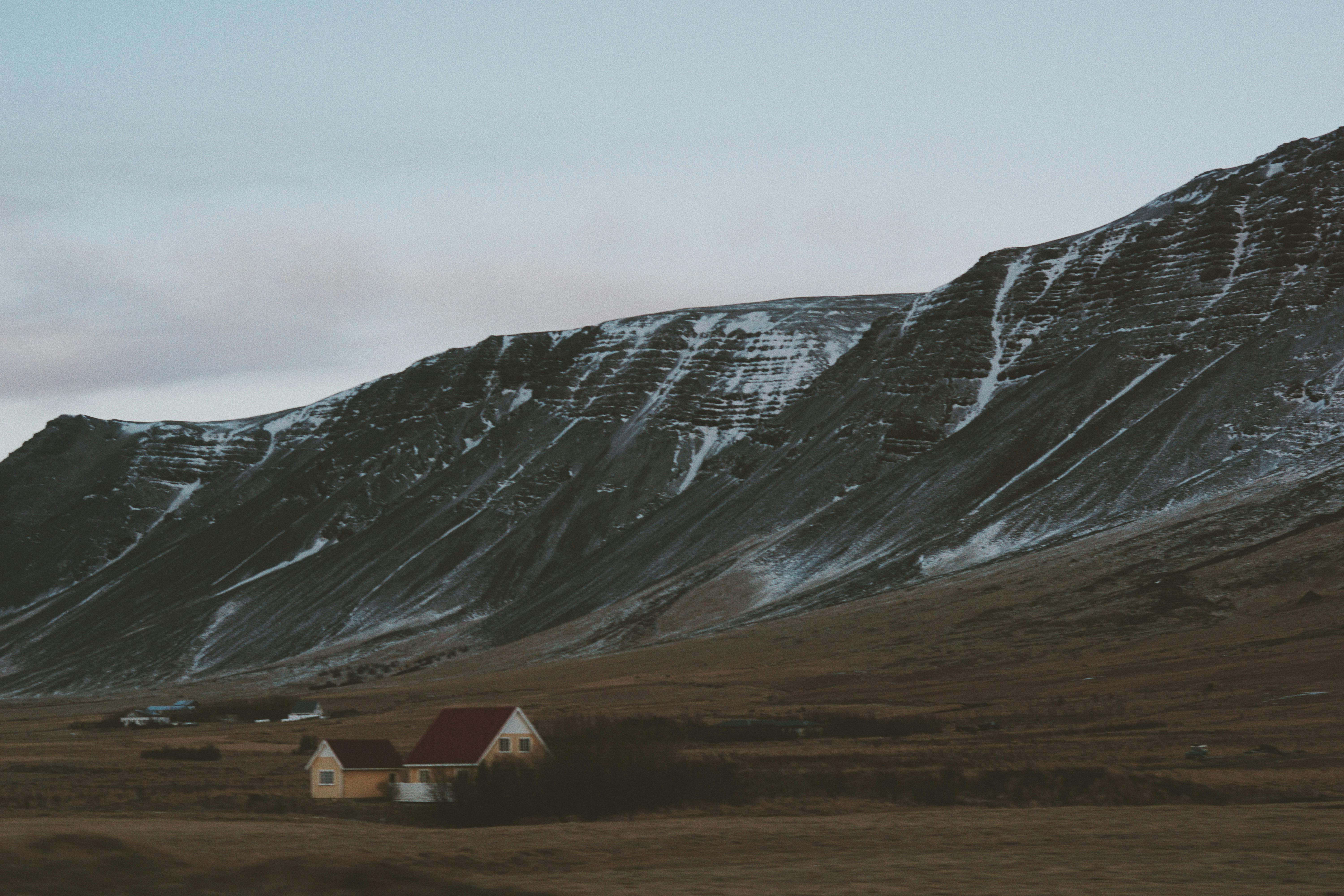 黄昏时，孤屋静立于雪山之畔，捕捉到一片宁静的冬日景象
