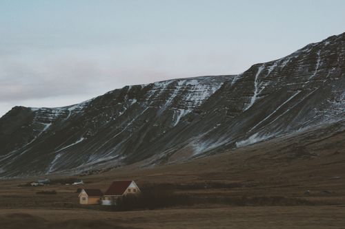Free Serene snowy mountain landscape with a lone house at dusk, capturing a peaceful winter scene. Stock Photo