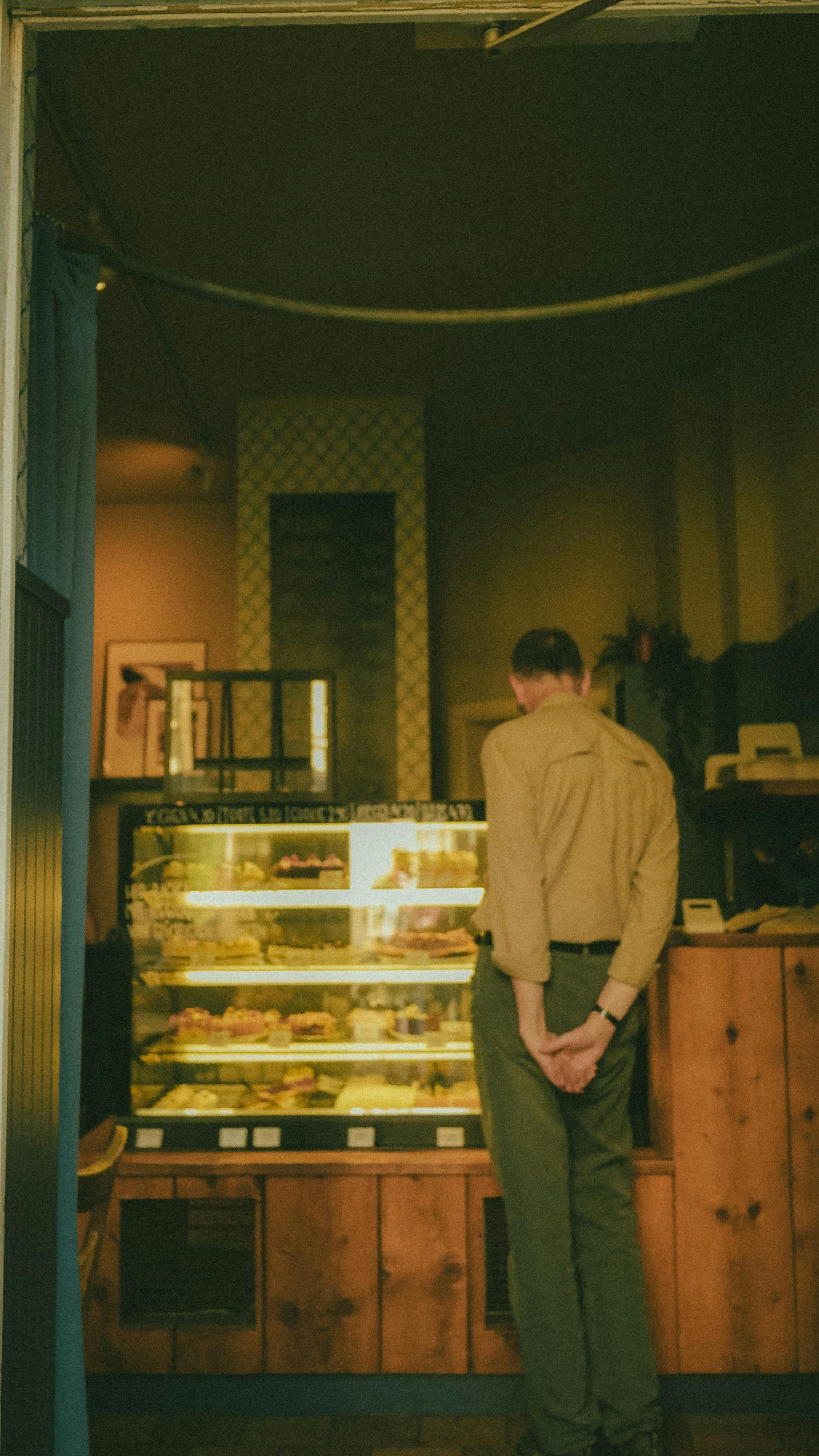 Man Contemplating Pastries in Cozy Cafe Interior