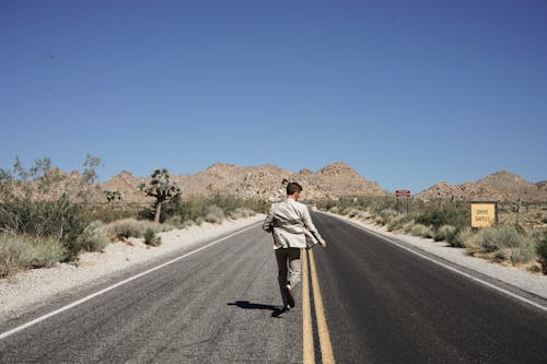 Man Wearing Gray Suit Jacket and Pants Running on Asphalt Road