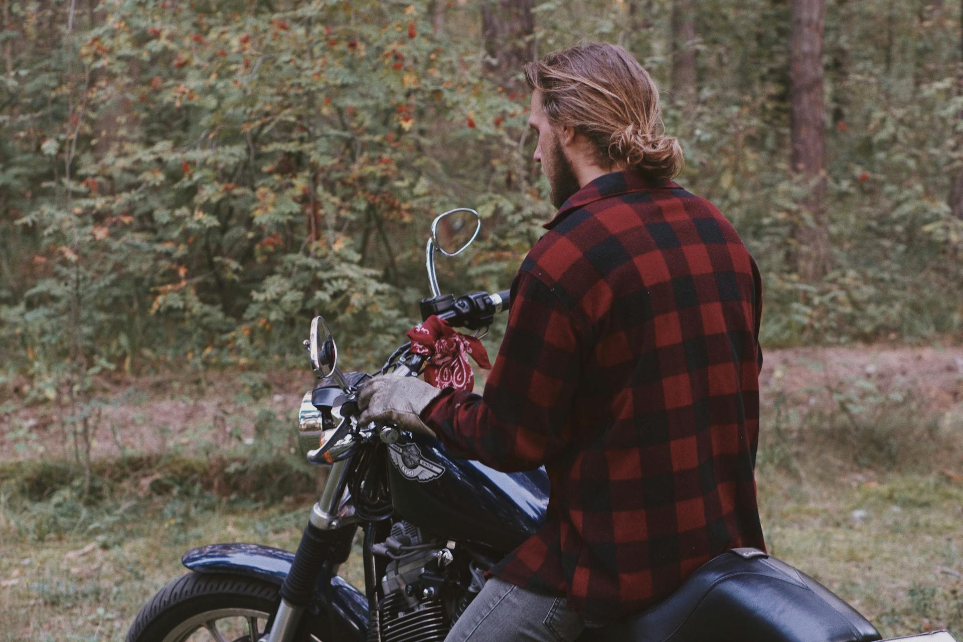 A man on a motorcycle rides through a forest, enjoying a leisurely outdoor adventure.