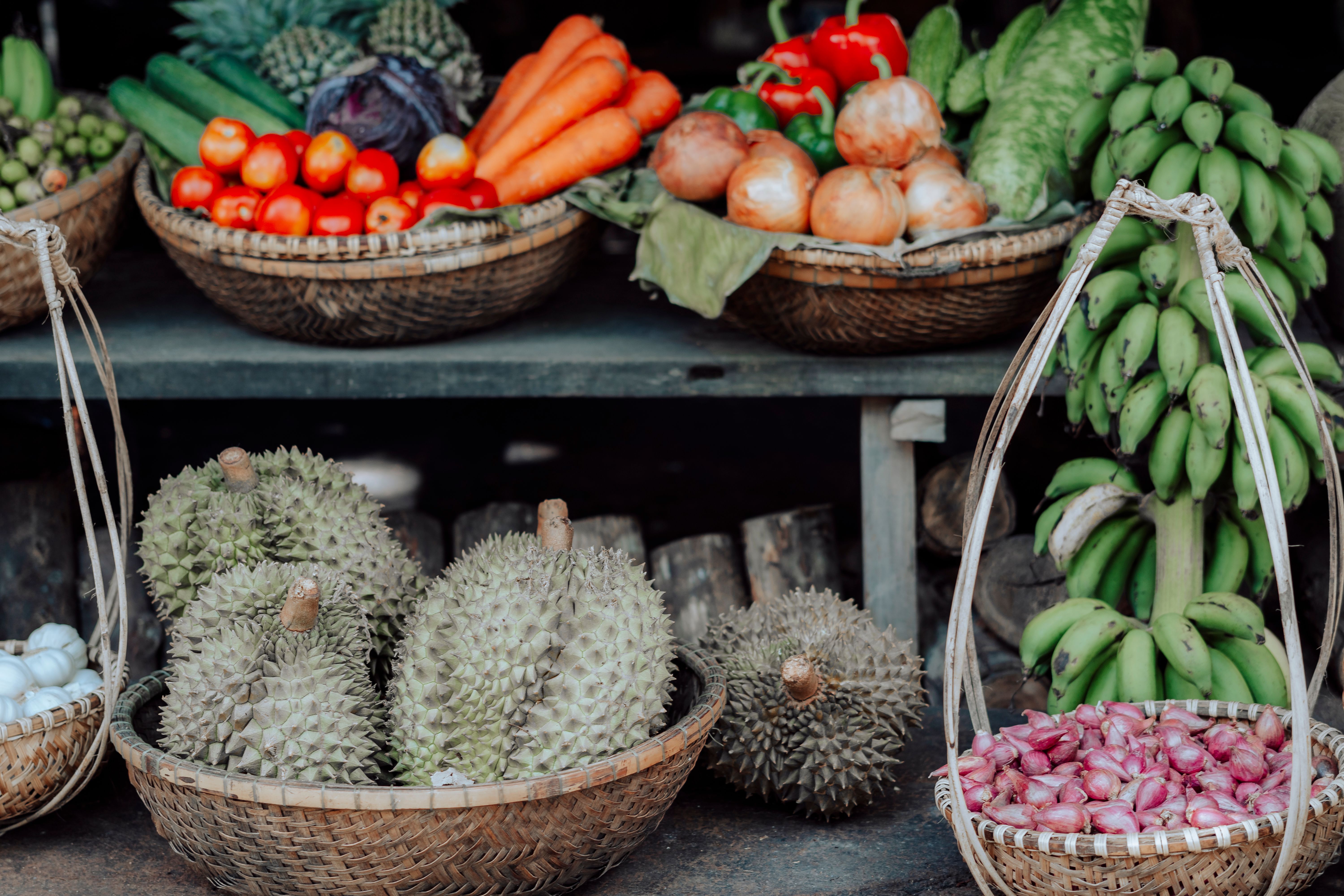 A diverse array of fresh vegetables and fruits displayed in baskets at a market stall.