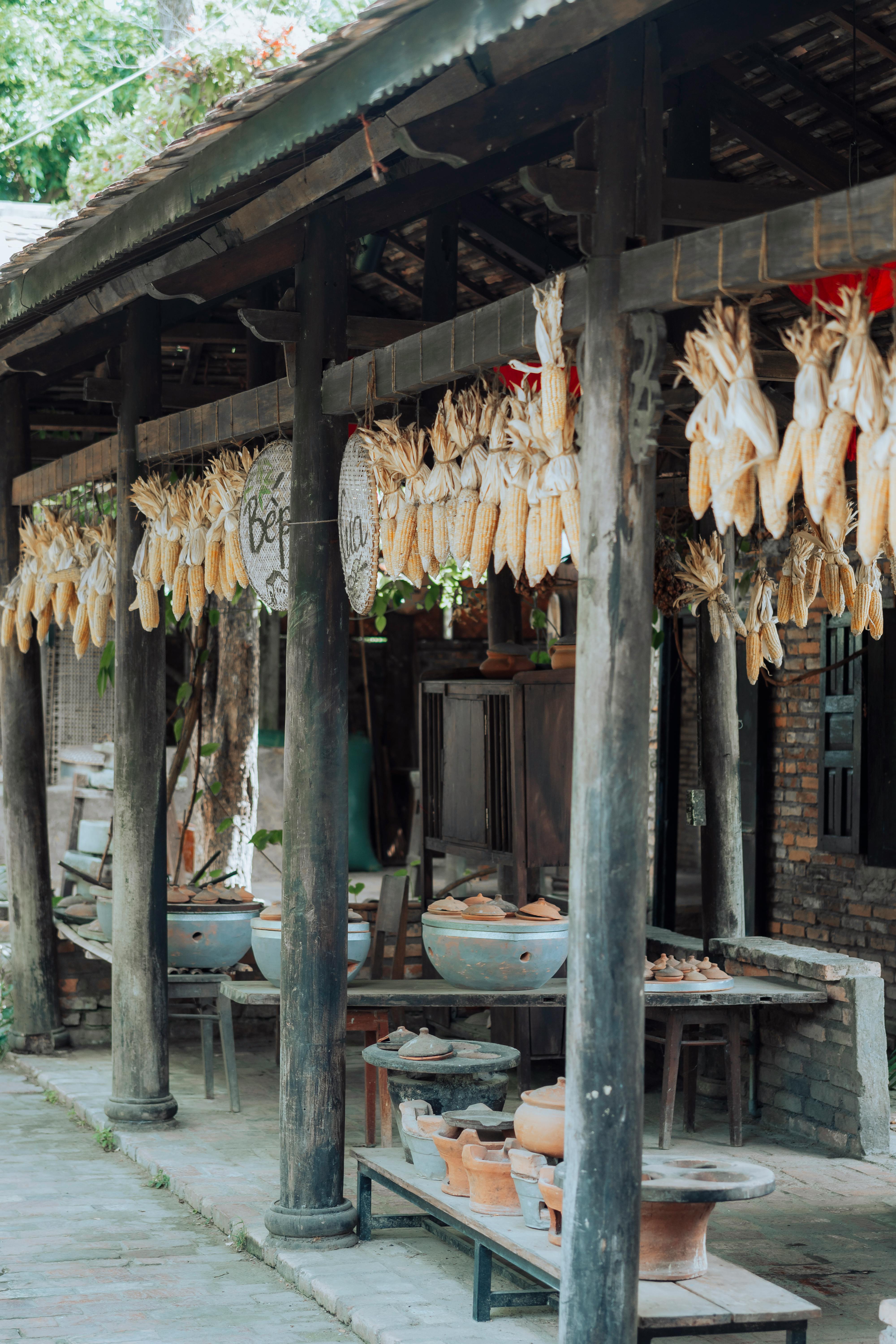 Rustic outdoor market with hanging corn and pottery, showcasing traditional craftsmanship.