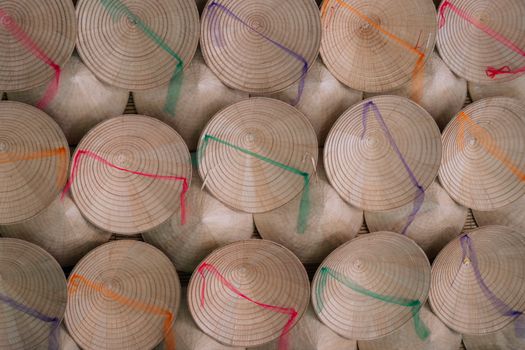 Top view of traditional woven bamboo hats with colorful strings arranged in rows, highlighting craftsmanship.
