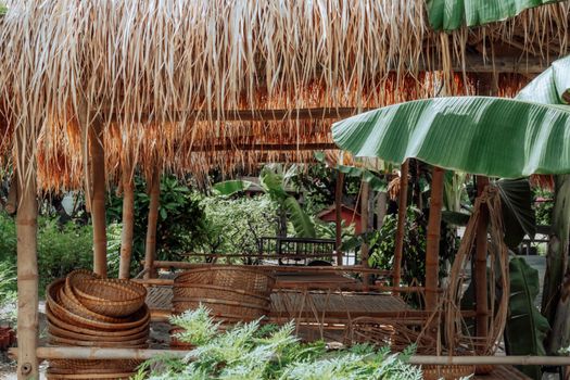 Charming outdoor tropical setting with bamboo huts and lush banana leaves, perfect for relaxation.