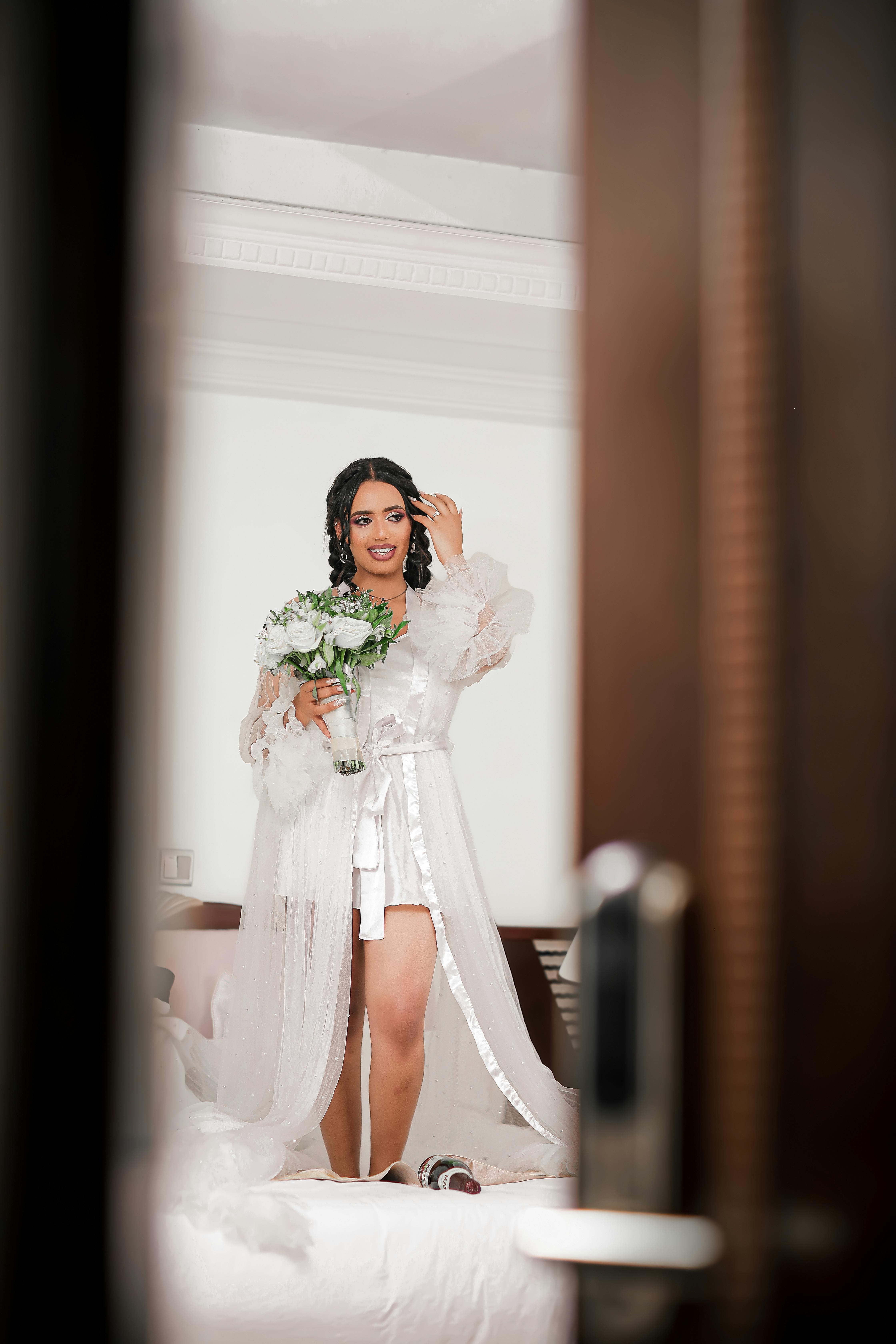 a bride in a white dress standing in front of a mirror