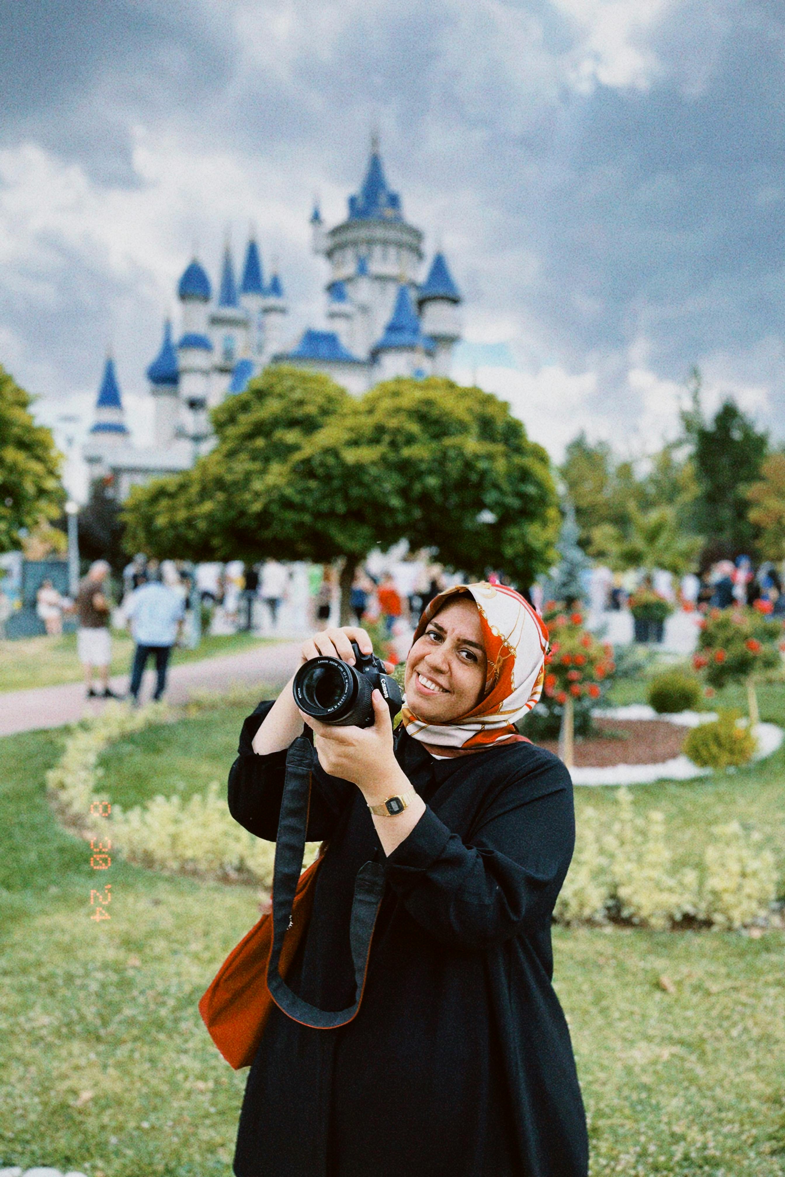 Smiling woman photographer holding a camera at Sazova Park, Turkey.