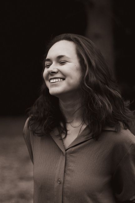 Stylish sepia portrait of a smiling woman outdoors, capturing natural elegance and joy.