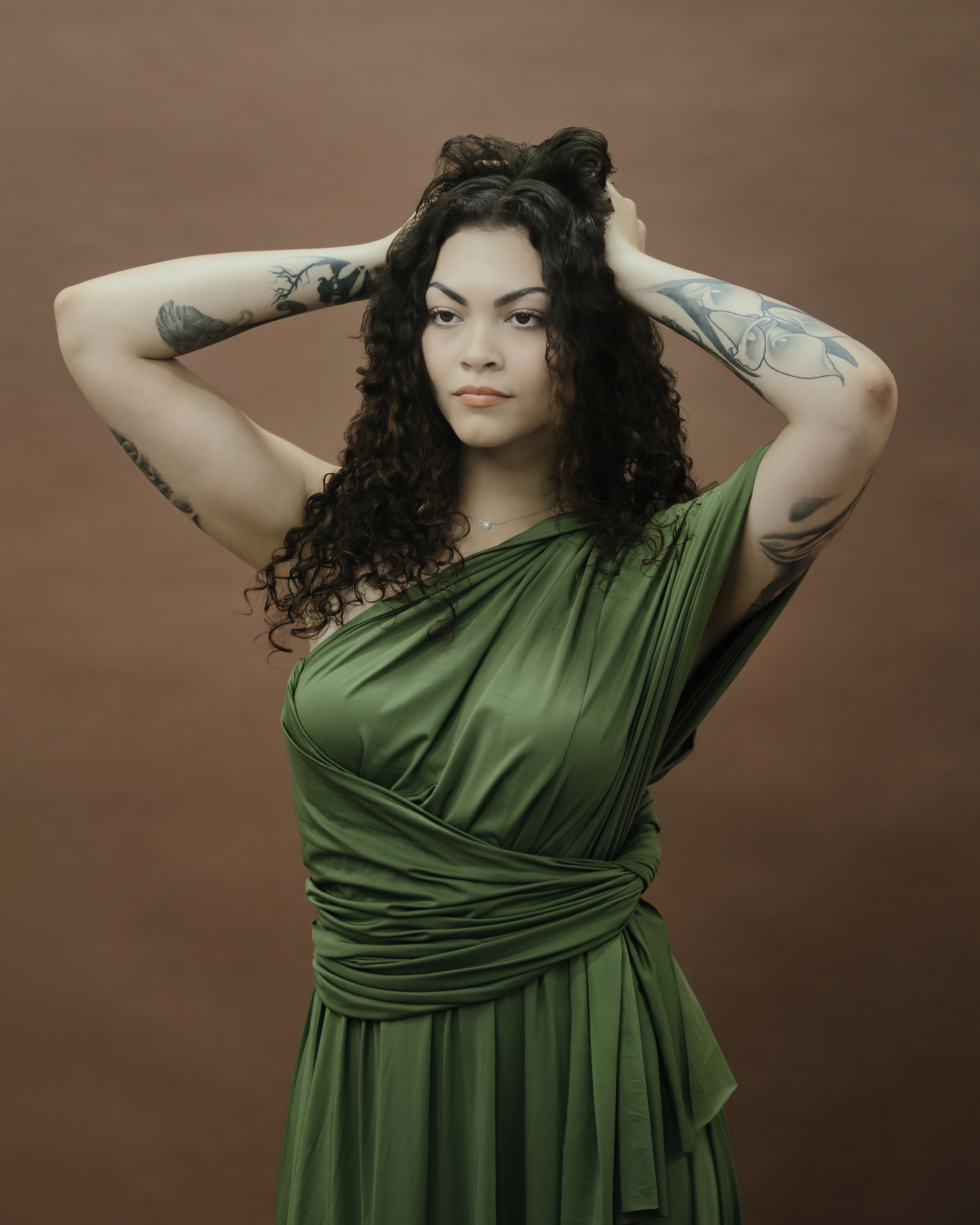 Stylish woman in a green dress posing confidently in a studio setting.
