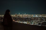 在洛杉矶的夜晚，天际线展现出壮丽的景象，而前景中模糊的人影增添了神秘感