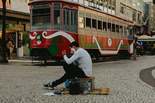 Candid scene in Curitiba with trams and a man seated on the historic street.